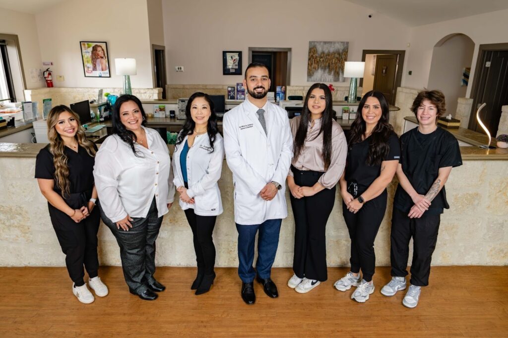 Complete Dental Studio team in modern dental office, showcasing diverse staff including dentist in white coat and supportive team members, emphasizing family-oriented care and advanced dental services.
